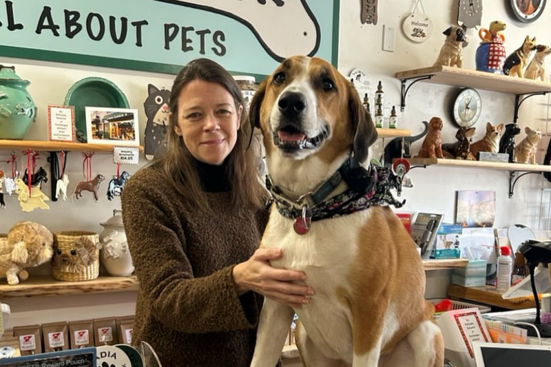 Person with a dog in a pet store with a sign in the background